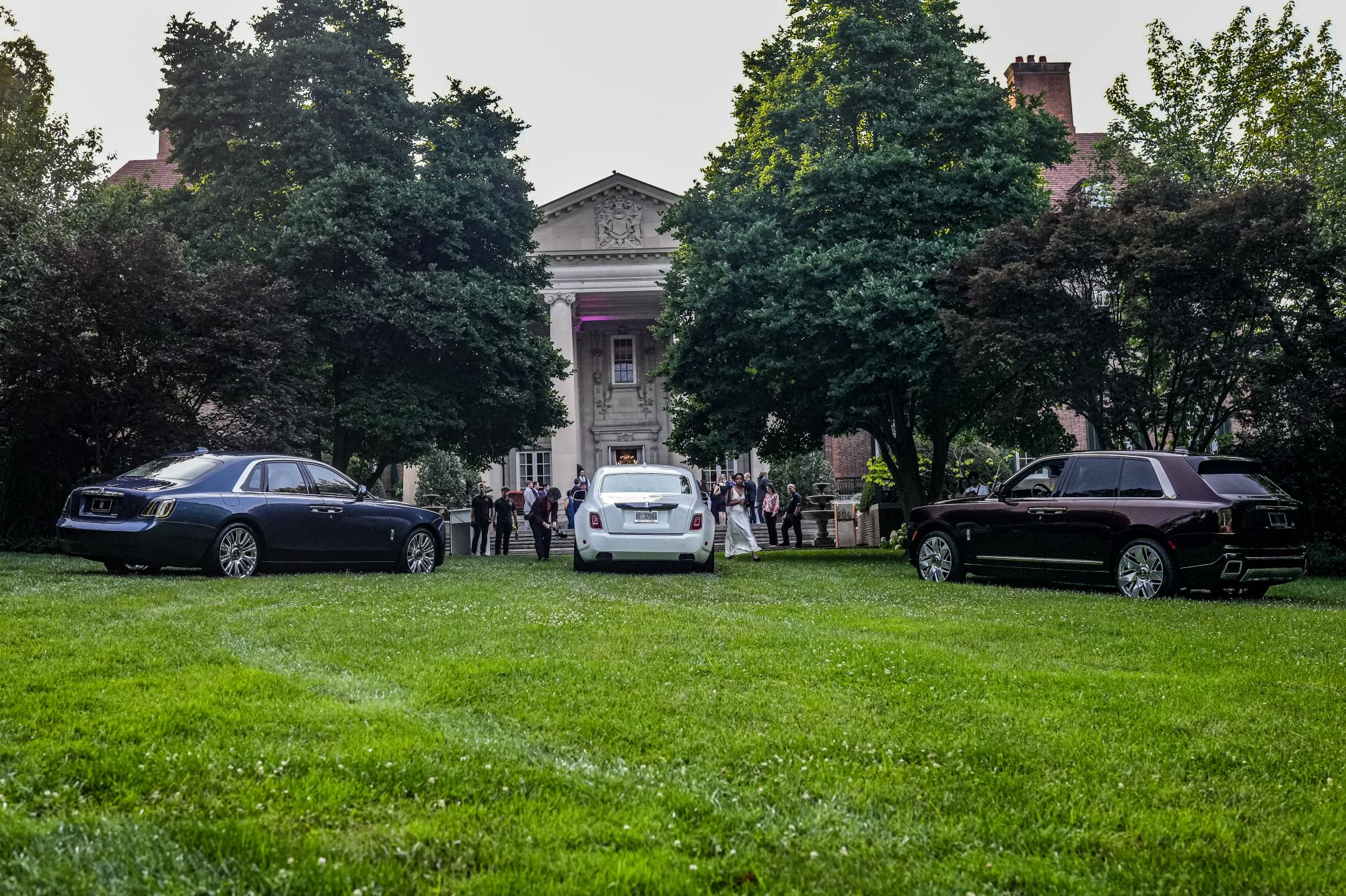 Three Rolls-Royce cars displayed on lush green grass in front of a grand building during America's 250th anniversary celebration.