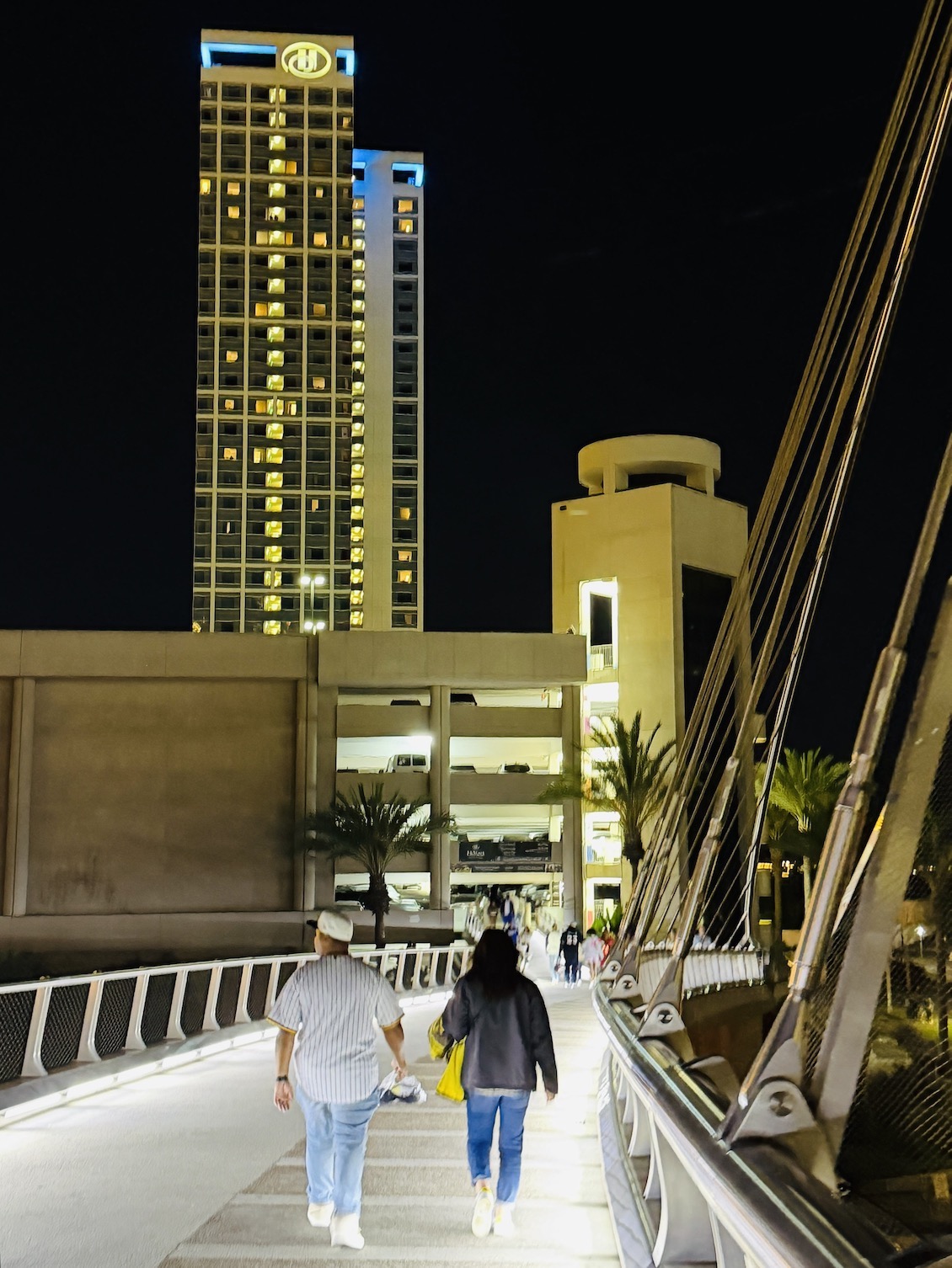 Couple walking along a lit pathway at night near the luxury Hilton San Diego Bayfront hotel.