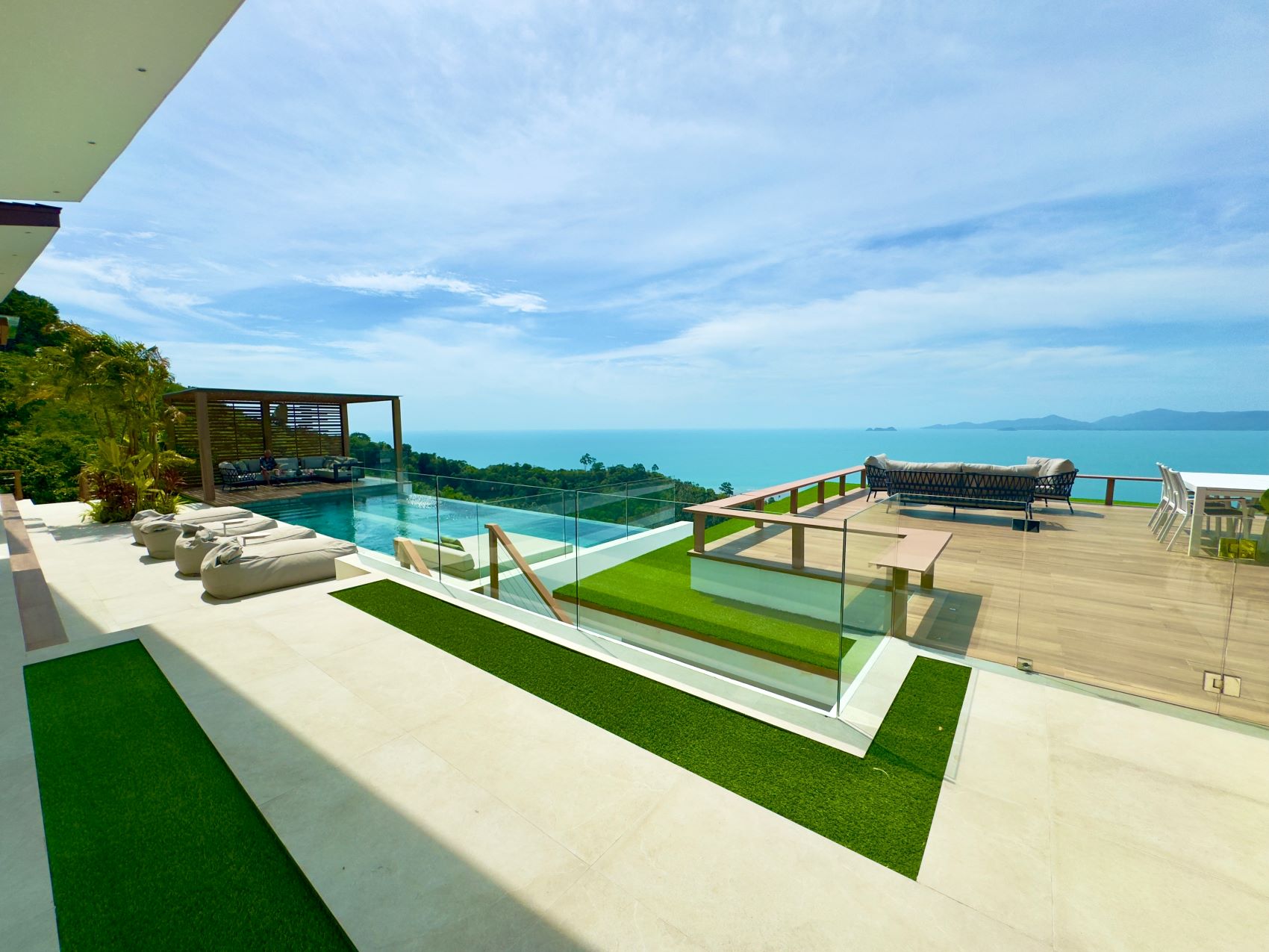 Luxurious villa with a pool and stunning ocean views, showcasing a stylish outdoor living space and surrounding greenery.