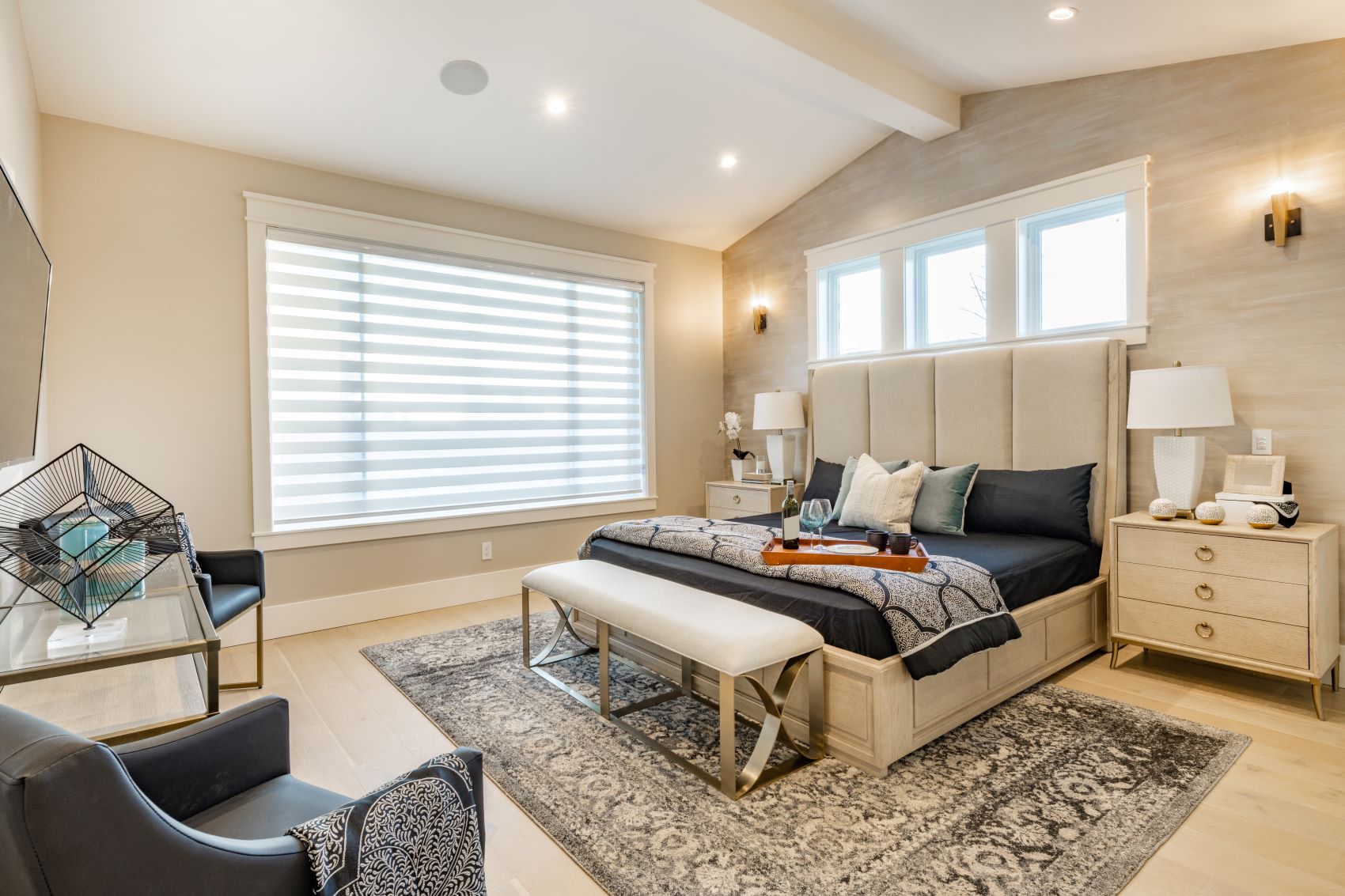 Modern luxury bedroom featuring natural light, layered textiles, a stylish bench, and elegant furnishings.