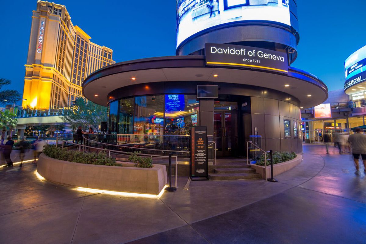 Davidoff of Geneva cigar lounge entrance illuminated at night with the Palazzo hotel in the background on a bustling street.