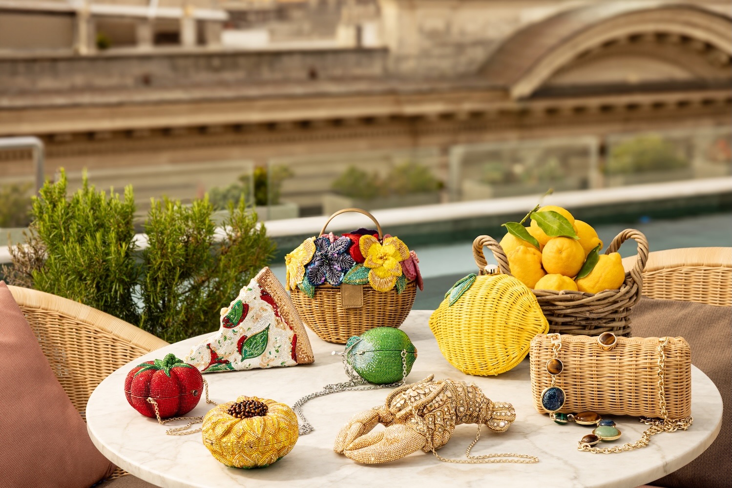 Colorful beaded handbags and decorative items displayed on a marble table with greenery and a poolside view in the background.