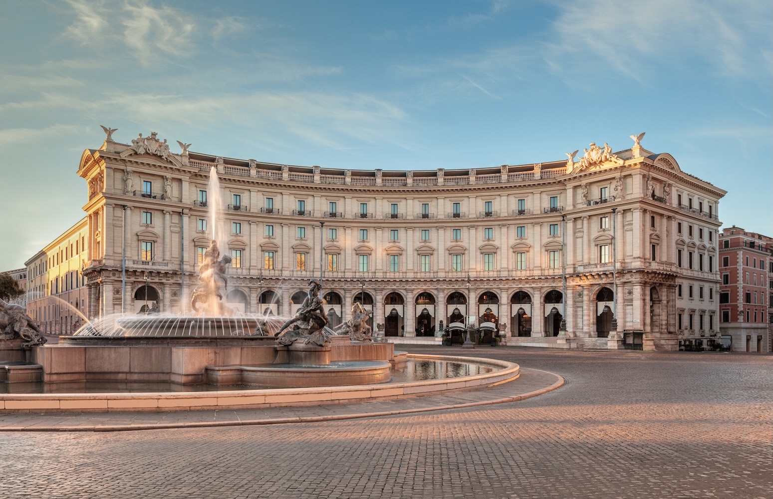 Elegant exterior view of the Anantara Palazzo Naiadi hotel in Rome, featuring a stunning fountain and classical architecture.