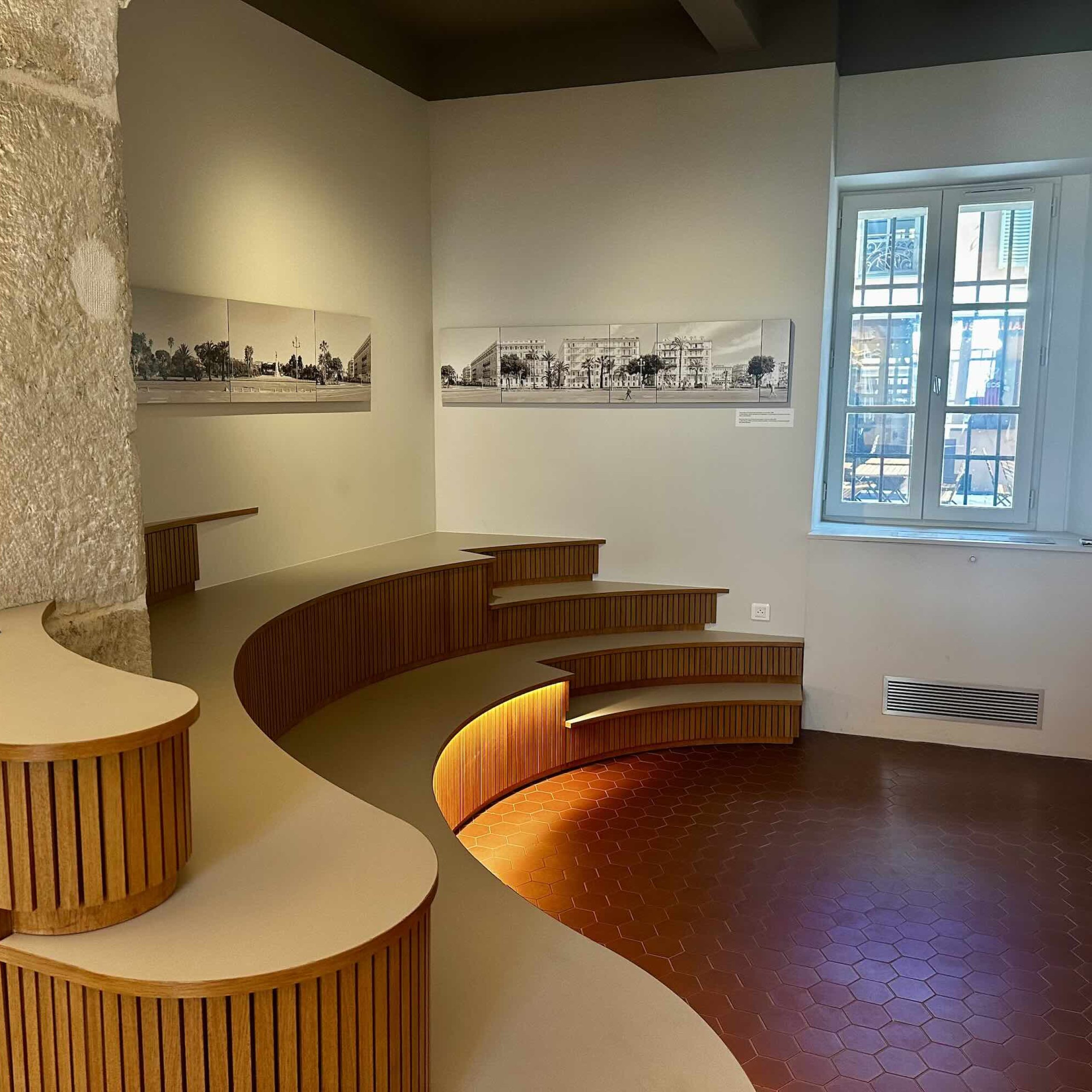 Modern interior space features curved wooden seating and artwork on the walls, creating a welcoming atmosphere for visitors.