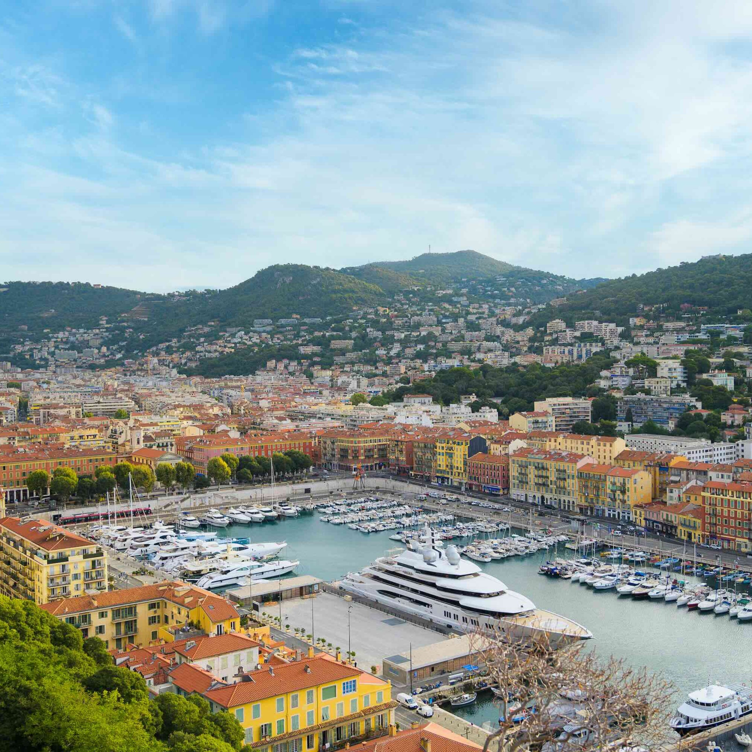 Aerial view of Nice's colorful waterfront, featuring yachts and the vibrant buildings along the coastline.