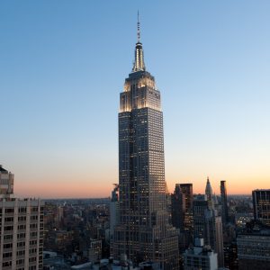 The Empire State Building illuminated against a twilight sky, showcasing its iconic Art Deco architecture amidst the New York City skyline.