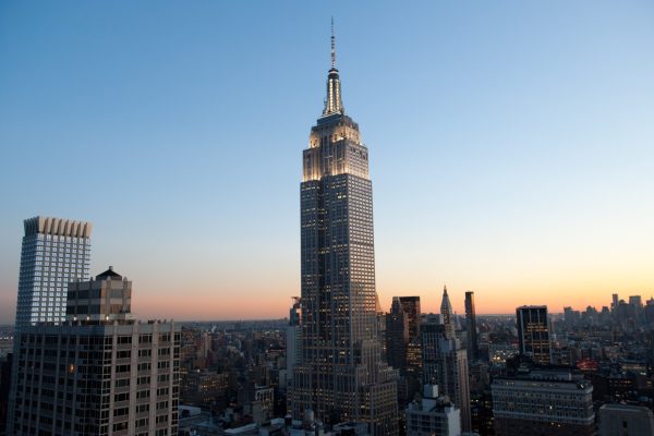 The Empire State Building illuminated against a twilight sky, showcasing its iconic Art Deco architecture amidst the New York City skyline.