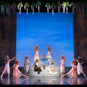 Dancers performing a scene from Anne of Green Gables at the Peacock Theatre, featuring floral decorations and a vibrant backdrop.