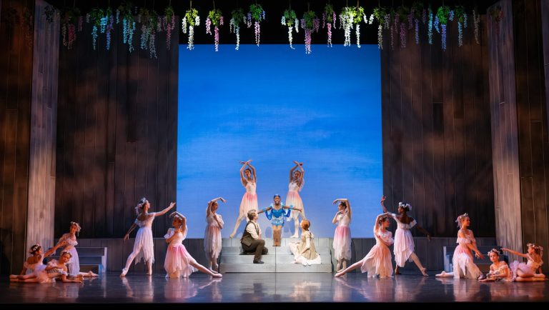 Dancers performing a scene from Anne of Green Gables at the Peacock Theatre, featuring floral decorations and a vibrant backdrop.