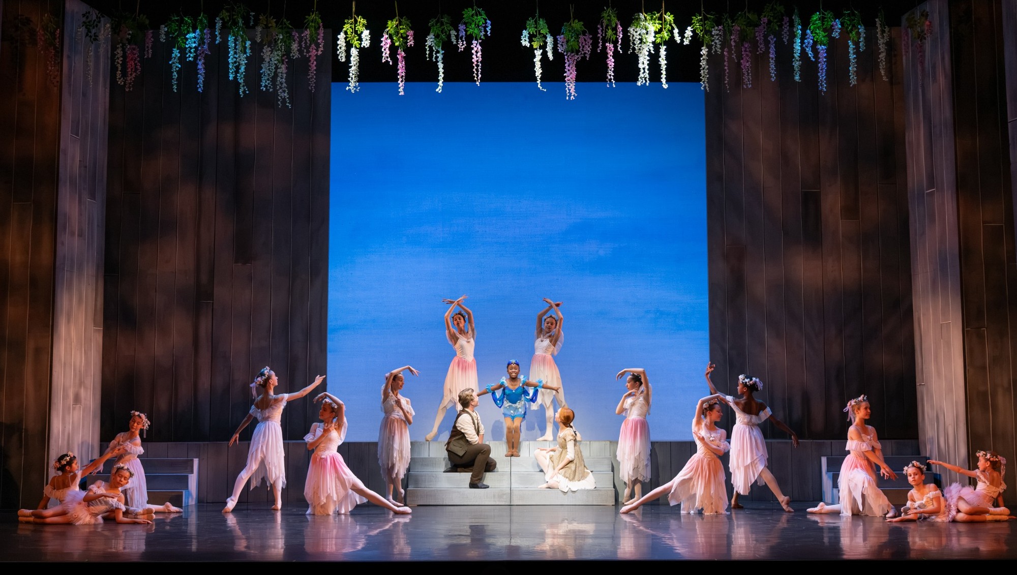 Dancers performing a scene from Anne of Green Gables at the Peacock Theatre, featuring floral decorations and a vibrant backdrop.