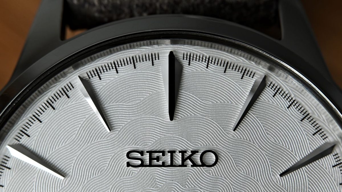 Seiko watch dial featuring wave-pattern texture and sharp silver hour markers against a silver background.