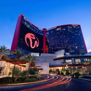 Luxury Conrad hotel entrance at Resorts World Las Vegas under evening sky with illuminated signage and palm trees.