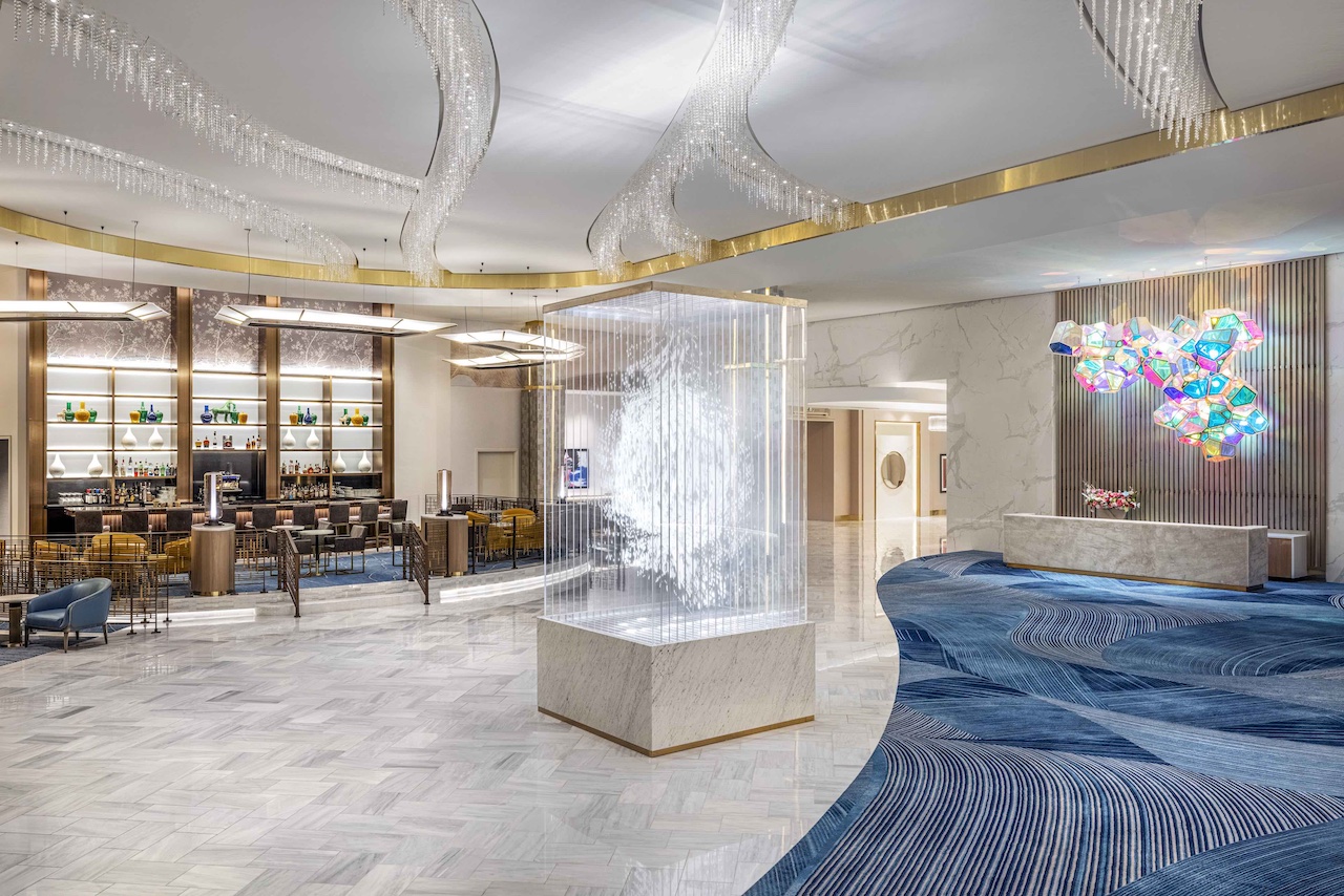 Luxurious lobby of Conrad Complete at Resorts World Las Vegas featuring a bar, unique lighting, and polished decor.