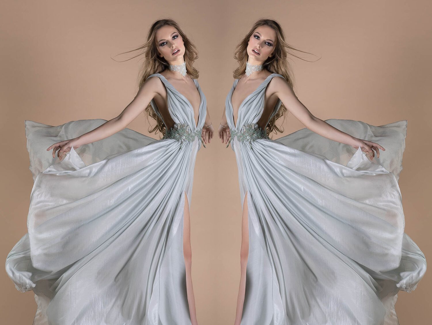 Model in a flowing light blue gown with intricate details, embodying grace and elegance in a soft pastel backdrop.
