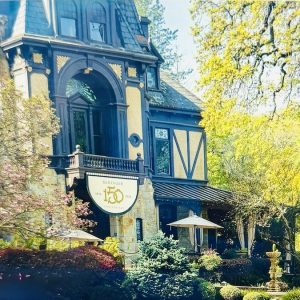 Beringer Winery's historic building adorned with a 150th anniversary sign, surrounded by lush greenery and colorful landscaping.