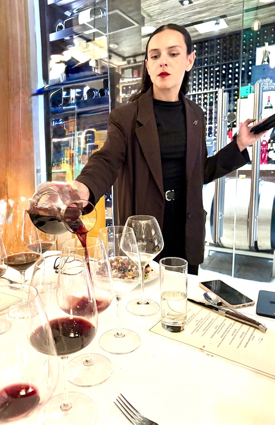 A woman pours red wine from a carafe into glasses at Wally's Wine & Spirits during the Beringer 150th anniversary event.