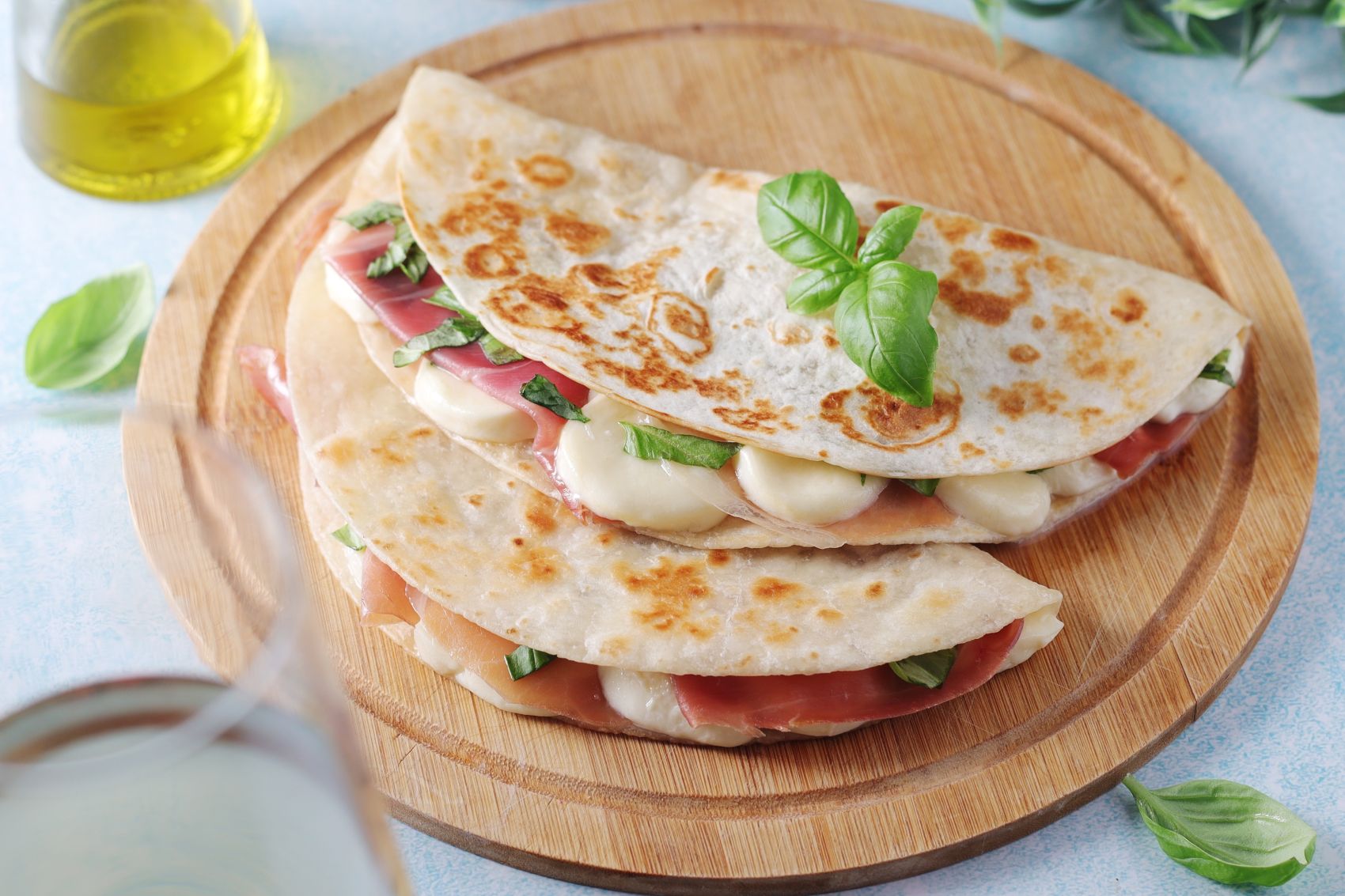 Protein wraps filled with ham, cheese, and basil on a wooden serving board, highlighting a nutritious meal option.
