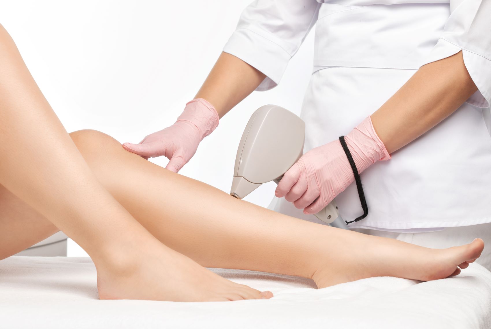 A technician performs laser hair removal on a client's leg, demonstrating the procedure in a clinical setting.