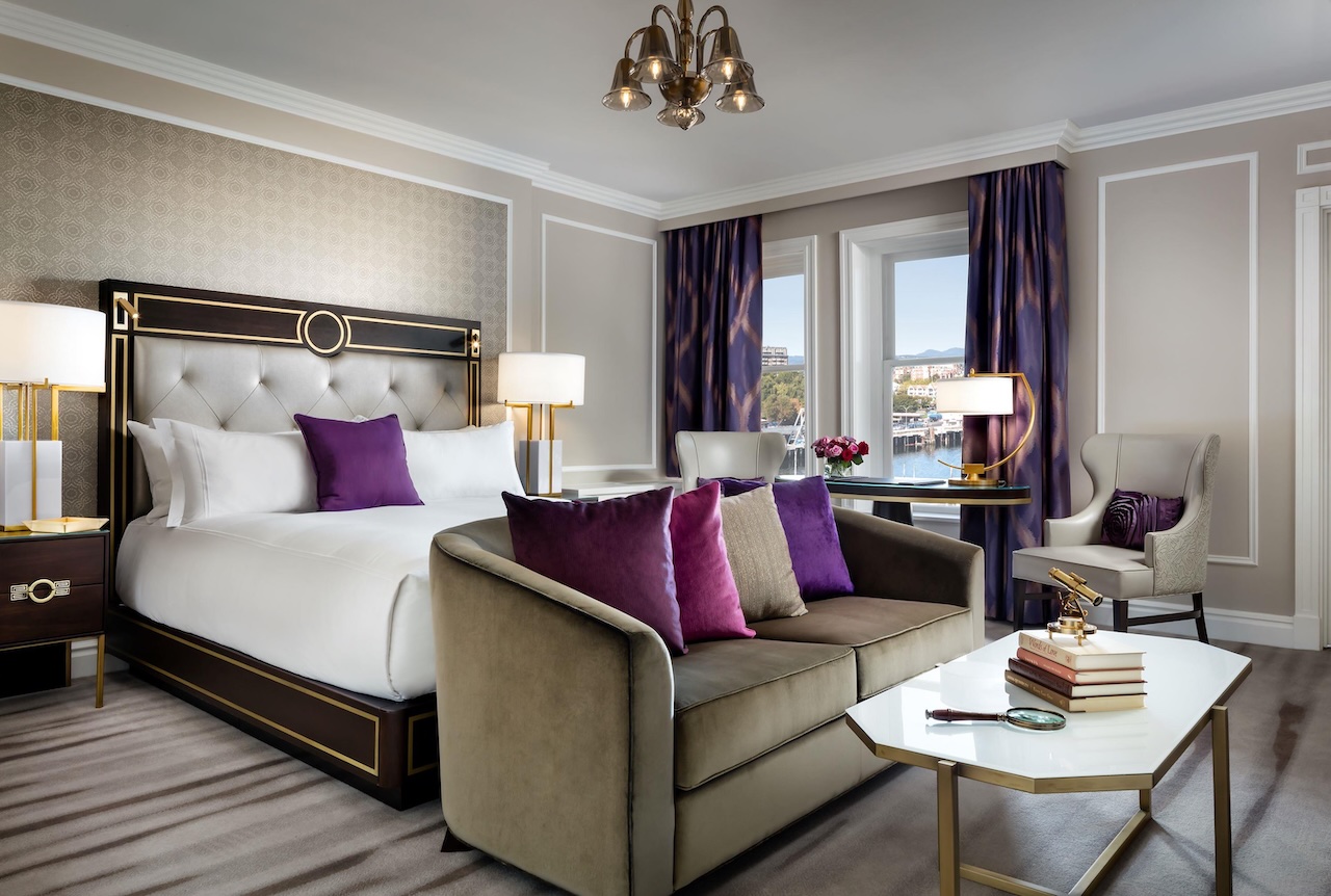 Elegant king room featuring plush bedding, stylish furnishings, and large windows with a view of Victoria's harbor.
