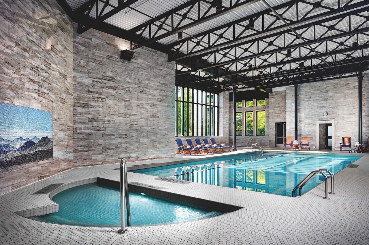 Indoor swimming pool at Fairmont Empress featuring elegant design, lounge chairs, and large windows for natural light.