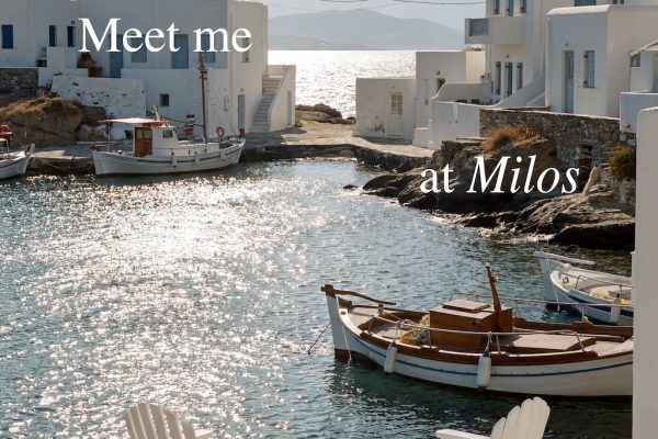Chairs by a serene waterfront in Milos, with boats and white buildings reflecting a summer vibe.