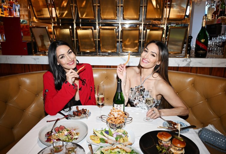 Twin sisters enjoying a luxurious dinner at Palms Las Vegas with an array of gourmet dishes and champagne.