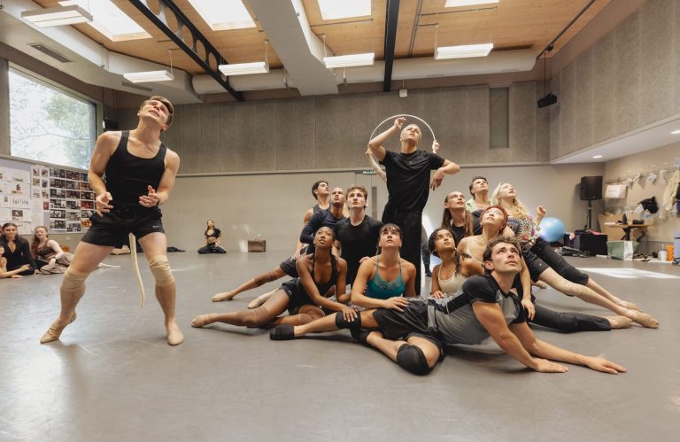 A diverse group of dancers rehearsing in a studio, showcasing dynamic poses and expressions during a performance.