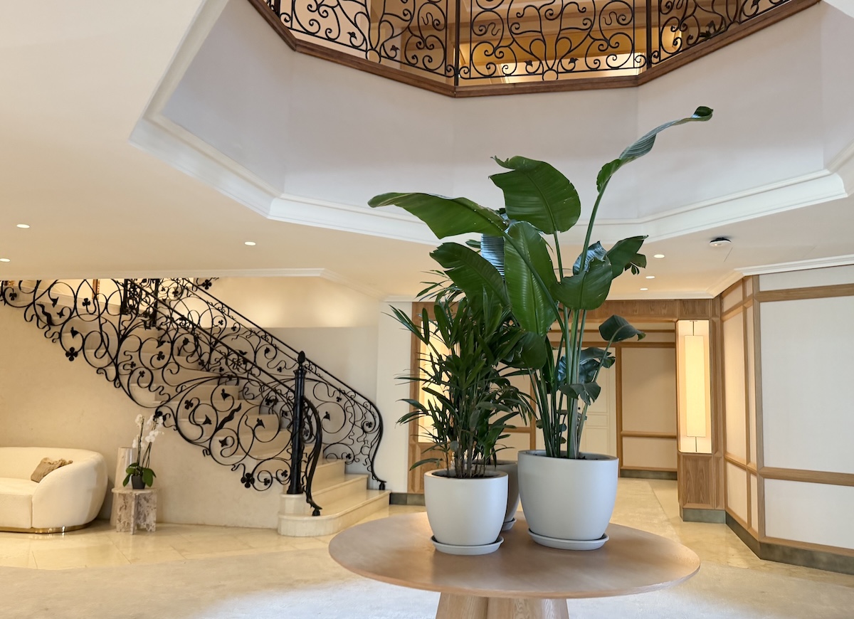Stylish interior featuring a staircase with ornate railing and potted plants in a bright, elegant space.