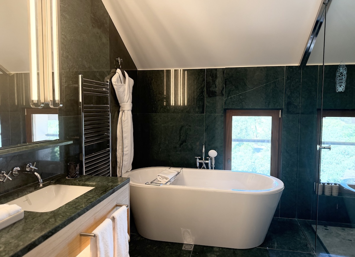 Luxurious bathroom featuring a freestanding tub, modern fixtures, and elegant green marble accents.