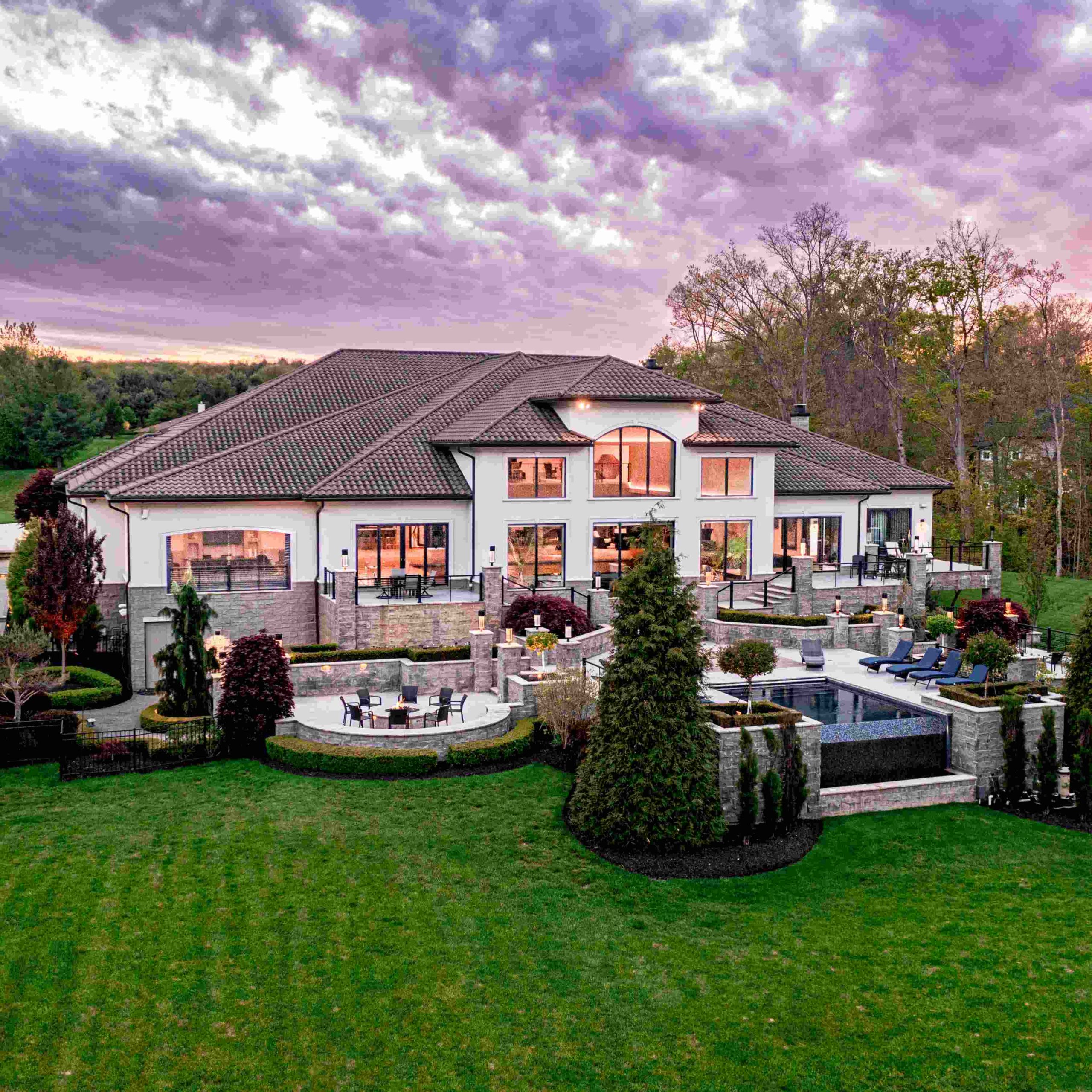 Luxury home in Hinckley featuring beautifully landscaped grounds, a pool, and stunning sunset views.