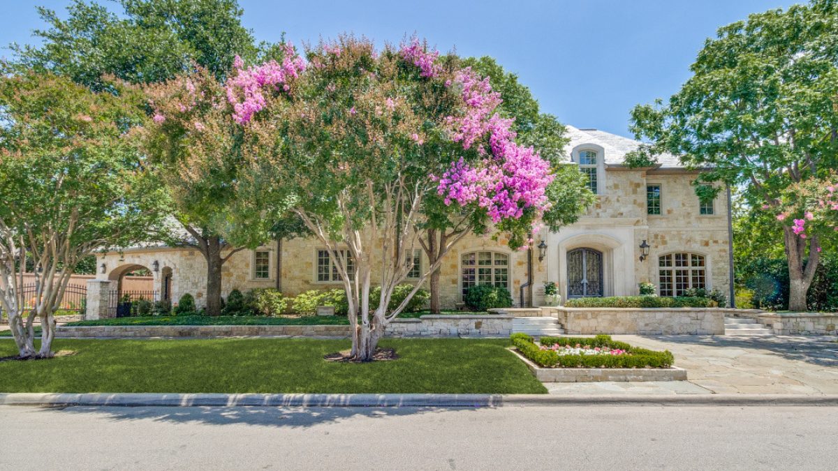 Luxurious stone home surrounded by lush trees and vibrant flowering plants in University Park.
