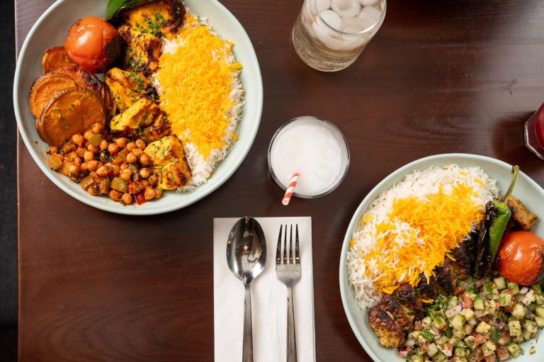 Vibrant Persian dishes featuring fluffy rice, grilled meats, roasted vegetables, and refreshing beverages on a wooden table.