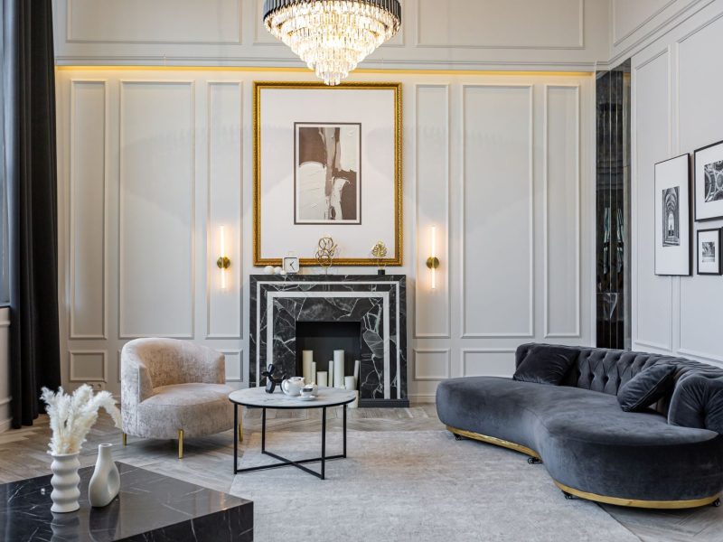 Luxurious living room featuring elegant furniture, a marble fireplace, and art decor against refined wall paneling.