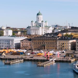 A scenic view of Helsinki's waterfront, featuring colorful markets, historic buildings, and the iconic cathedral.