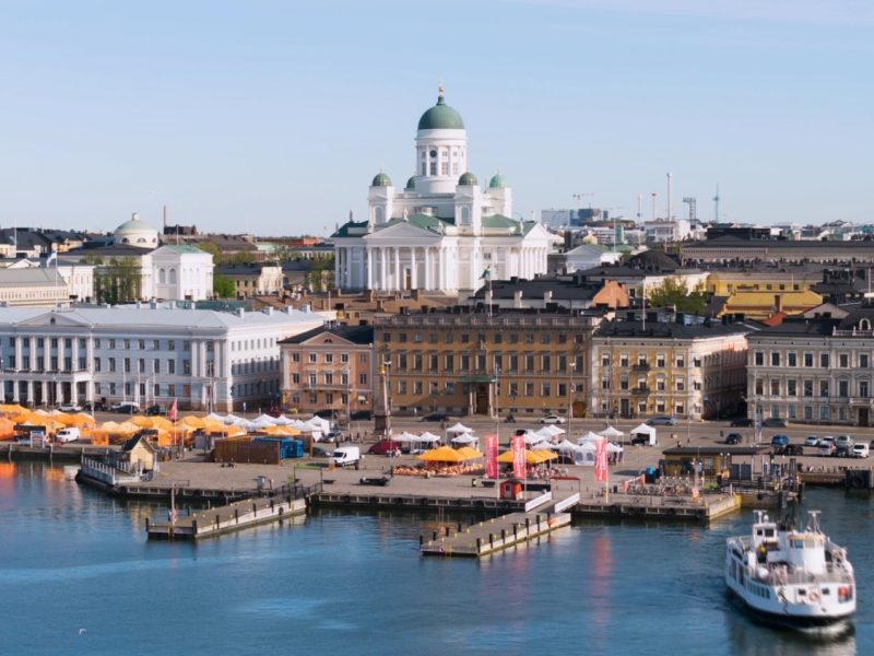 A scenic view of Helsinki's waterfront, featuring colorful markets, historic buildings, and the iconic cathedral.