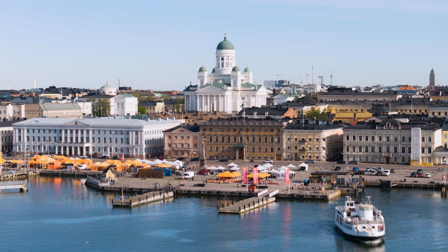 A scenic view of Helsinki's waterfront, featuring colorful markets, historic buildings, and the iconic cathedral.