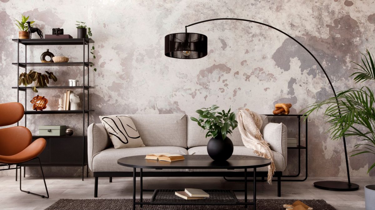 A stylish living room featuring a beige sofa, black coffee table, and decorative plants against a textured wall.