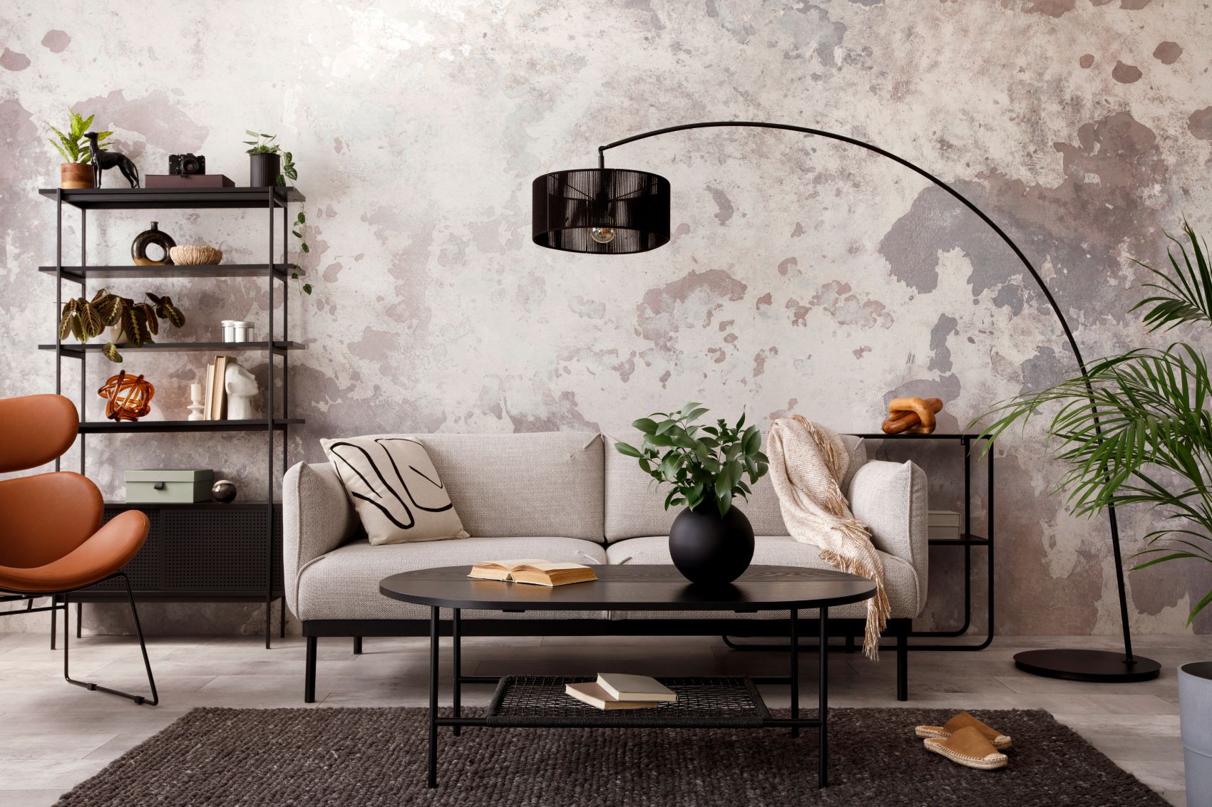 A stylish living room featuring a beige sofa, black coffee table, and decorative plants against a textured wall.