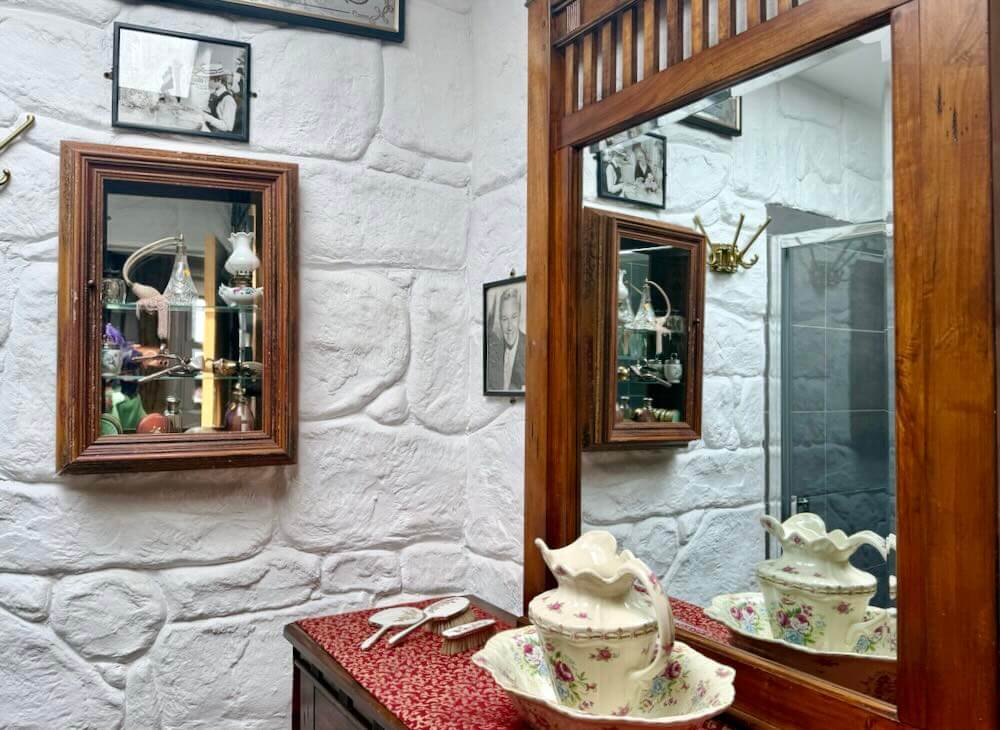 Elegant bathroom featuring historic artefacts, a decorated vanity, and a mirror reflecting the unique decor.