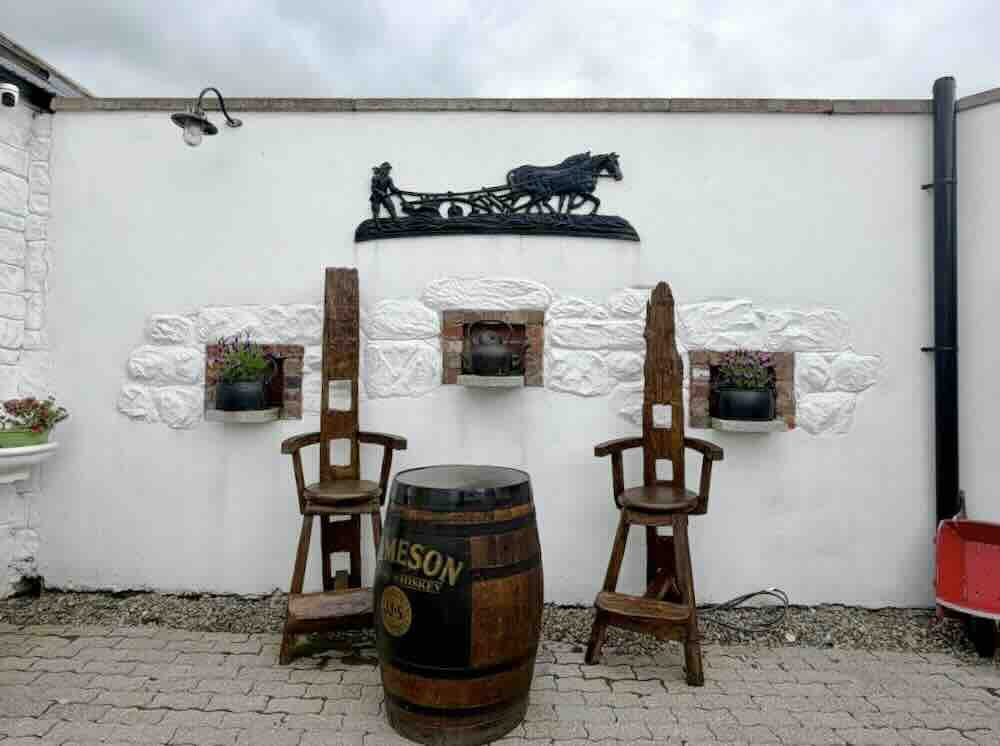 Historic artefacts and wooden chairs fill the wall of a luxury Irish guesthouse, highlighting its unique charm and character.