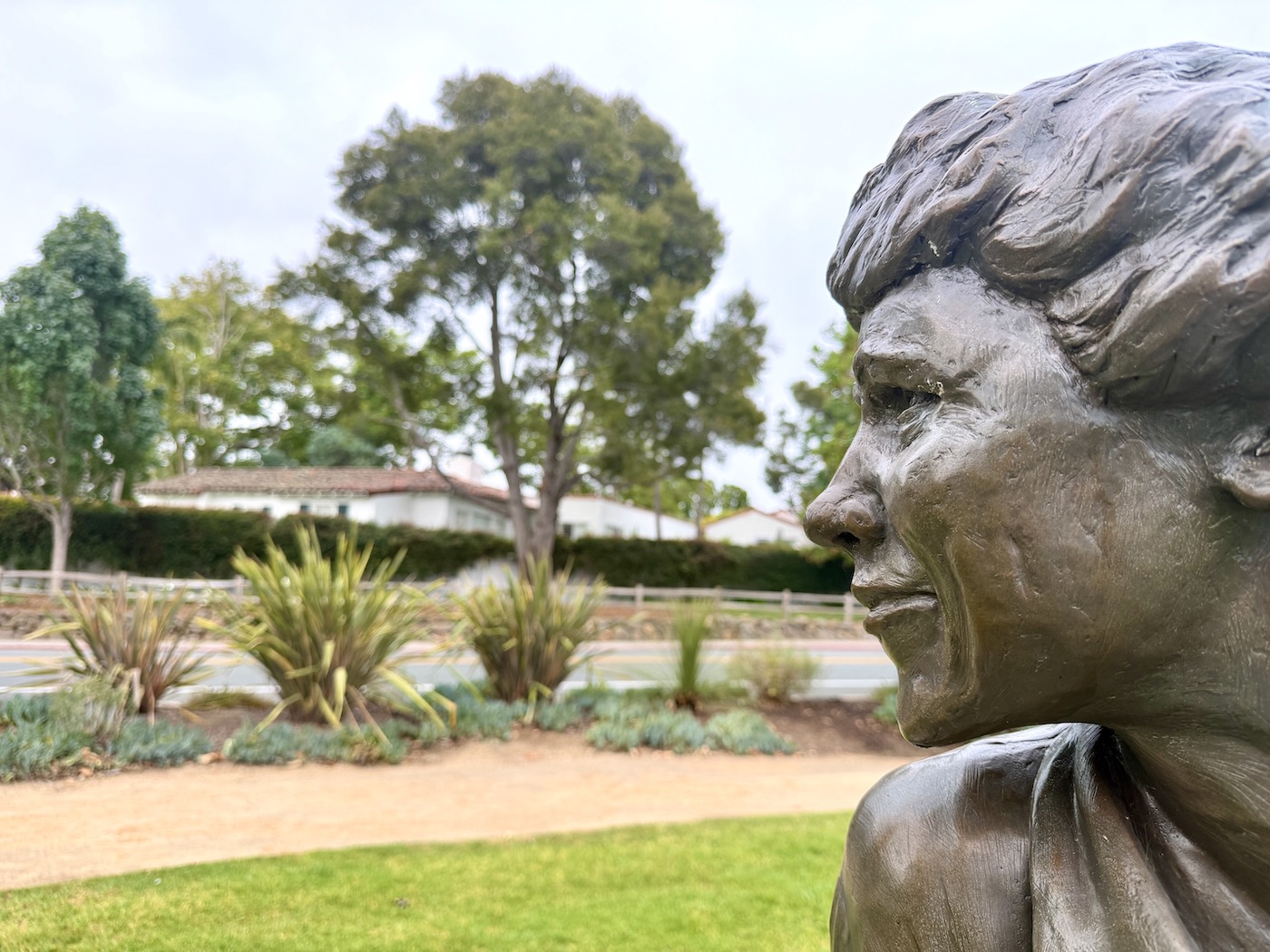 Bronze bust of architect Lilian Rice, showcasing her profile against a landscaped background near The Inn at Rancho Santa Fe.