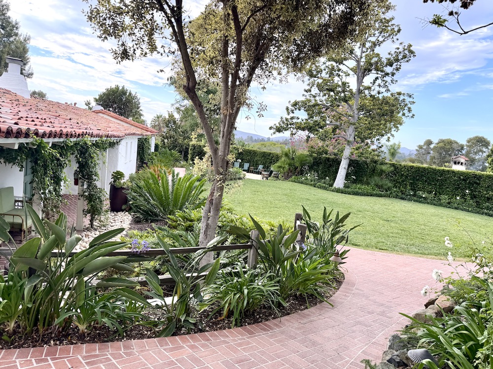 Cottages nestled among lush gardens and pathways at The Inn at Rancho Santa Fe, showcasing a serene outdoor setting.