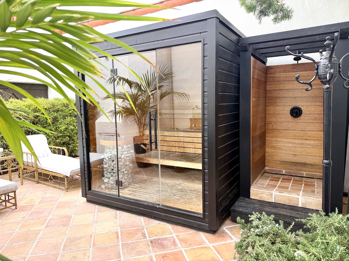 Spa area featuring a glass-walled sauna beside an outdoor shower and surrounded by greenery at The Inn at Rancho Santa Fe.