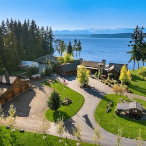 Aerial view of a waterfront estate in the Pacific Northwest, showcasing lush greenery and scenic water views.