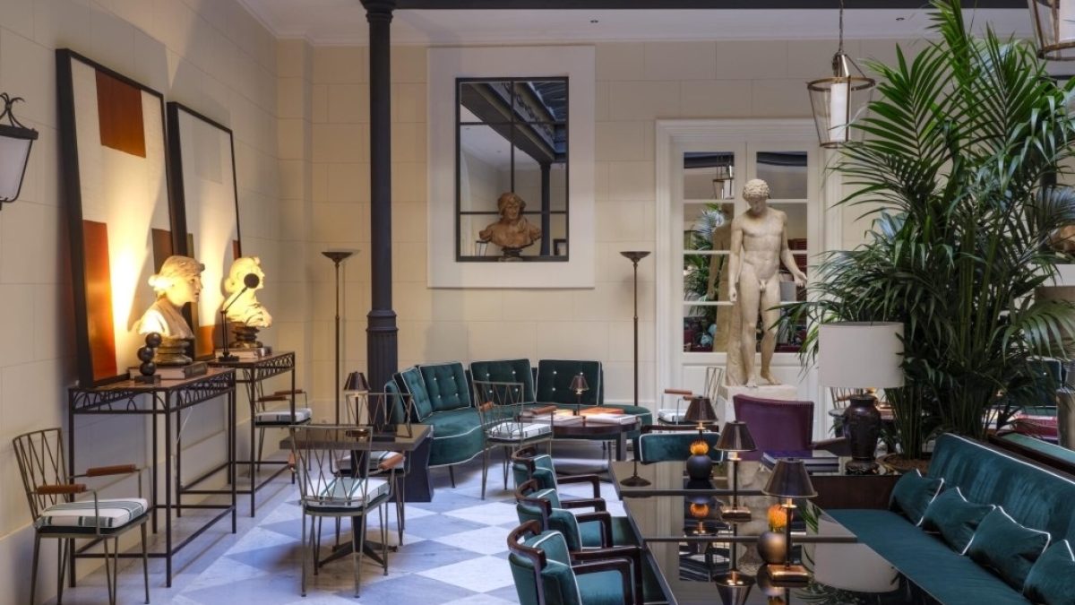 Elegant lounge area at Casa J.K. Place Roma featuring green velvet seating, decorative sculptures, and ambient lighting.