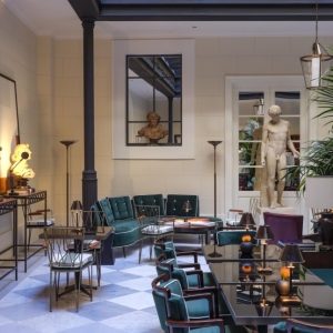 Elegant lounge area at Casa J.K. Place Roma featuring green velvet seating, decorative sculptures, and ambient lighting.
