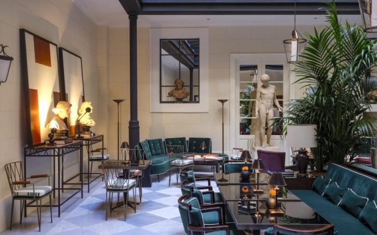Elegant lounge area at Casa J.K. Place Roma featuring green velvet seating, decorative sculptures, and ambient lighting.