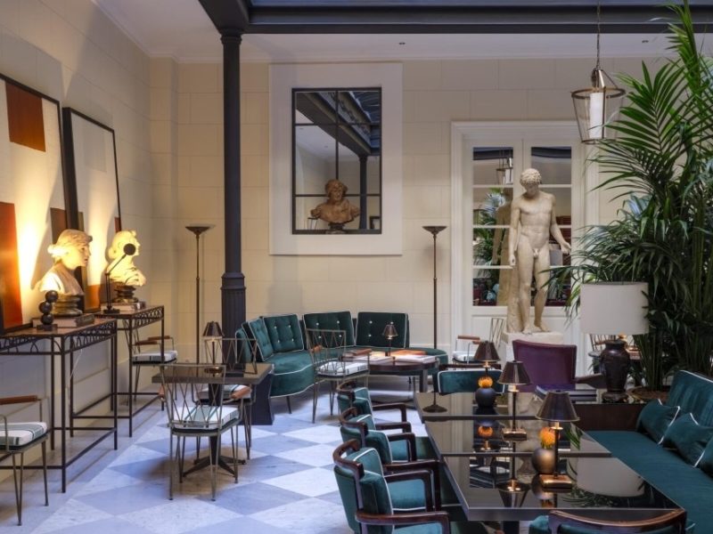 Elegant lounge area at Casa J.K. Place Roma featuring green velvet seating, decorative sculptures, and ambient lighting.