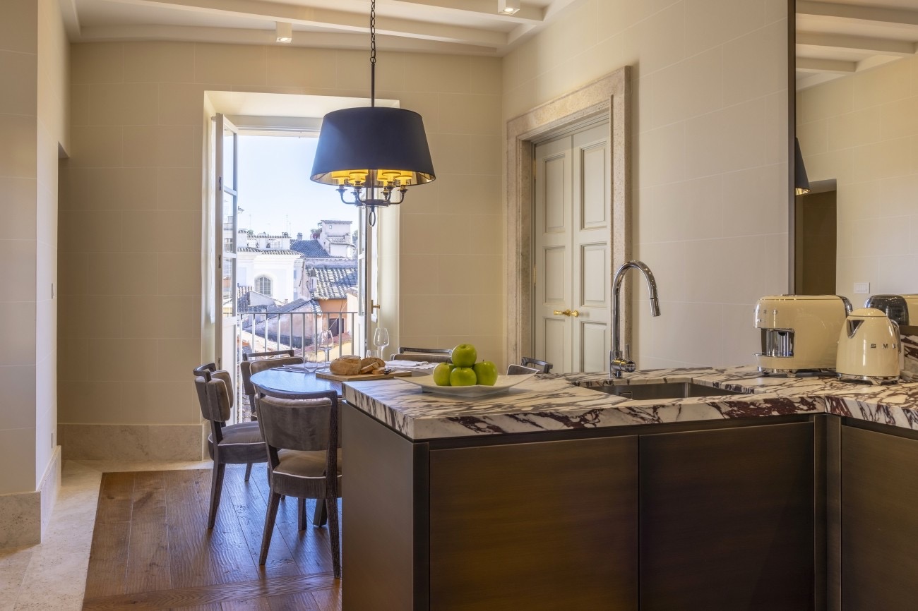 Stylish kitchen interior at Casa J.K. Place Roma, featuring a marble countertop, modern appliances, and a view of Rome.