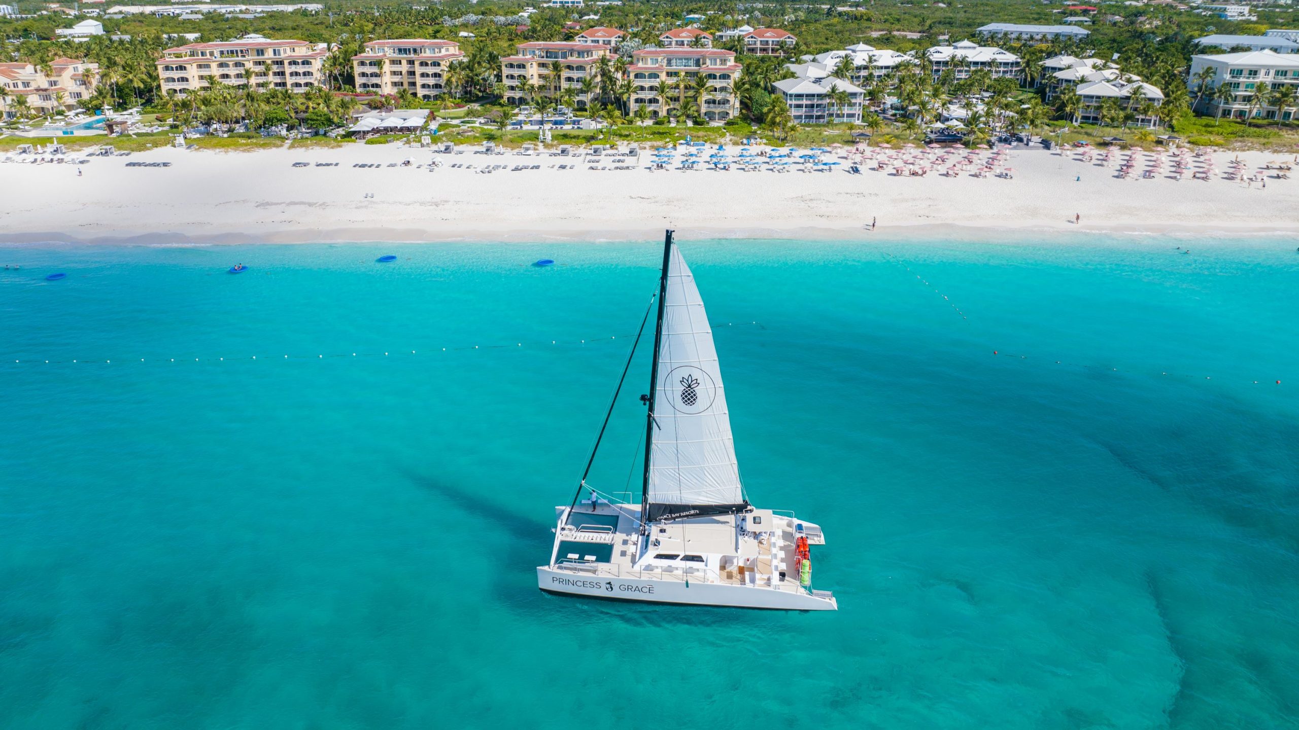 A catamaran named Princess Grace sailing in the clear turquoise waters off the beach in Turks and Caicos.